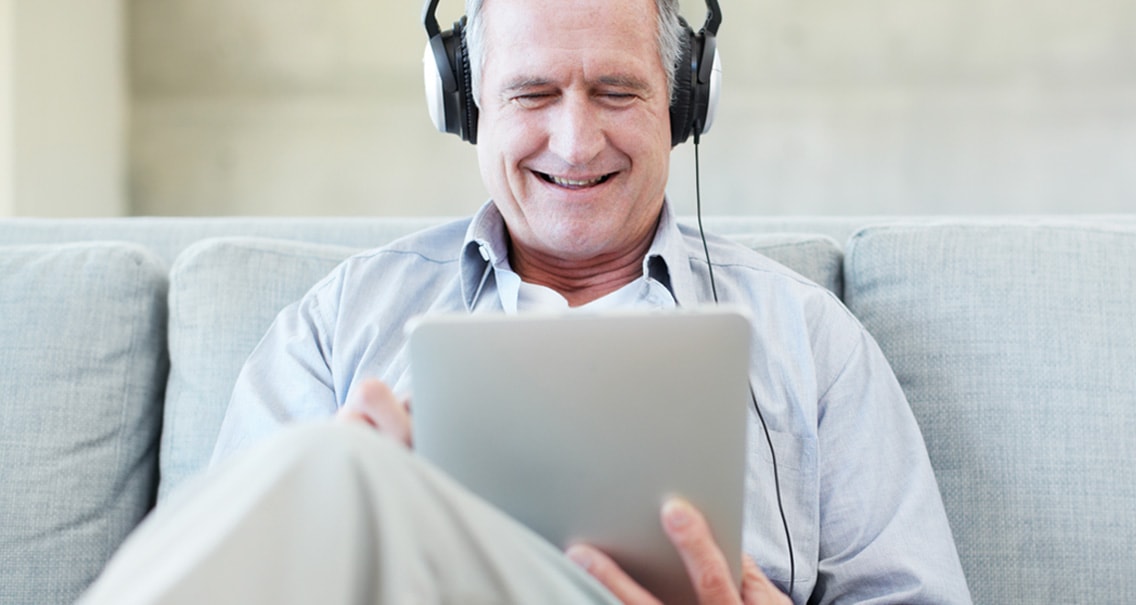 Man sitting on a couch checking his hearing with the online hearing test 