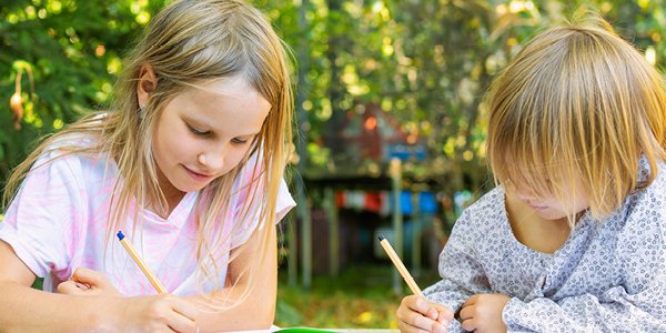 To børn sidder i naturen og tegner