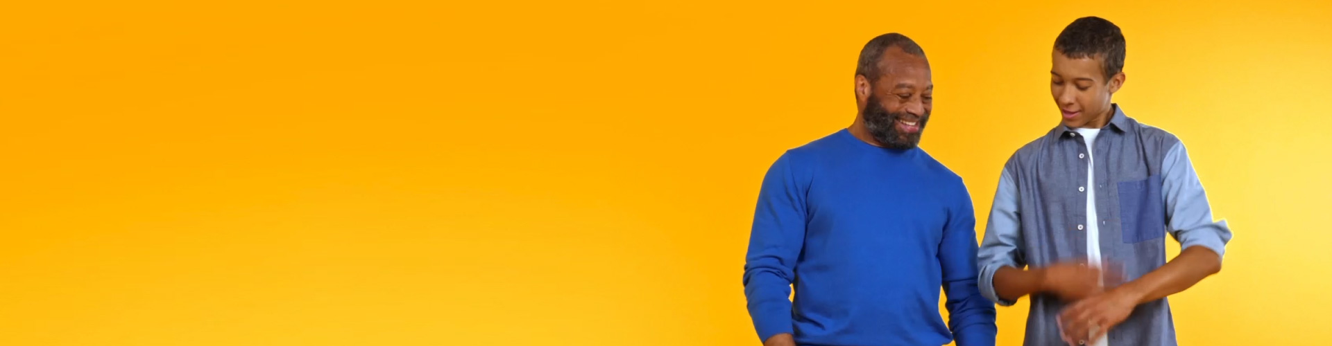 A grandfather wearing Philips HearLink and connecting with his teenage grandson while dancing to music. 