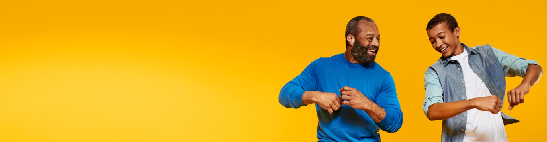 A grandfather wearing Philips HearLink and connecting with his teenage grandson while dancing to music. 