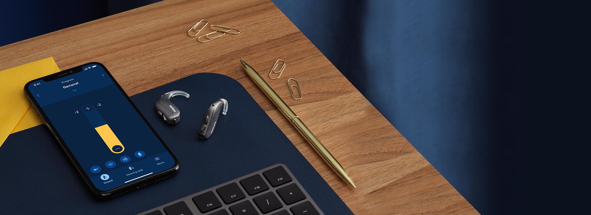 Philips HearLink miniRITE hearing aids next to a smartphone with the Philips HearLink 2 app open. 