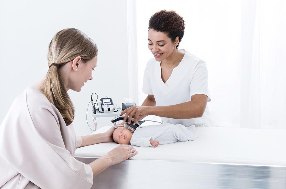 Audiologist screening the Auditory Brainstem response of a newborn baby while its mother hold its head softly