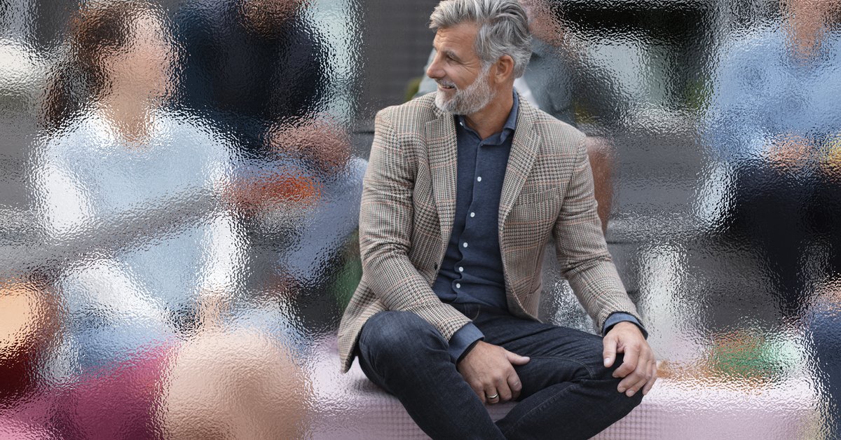 Un homme portant des aides auditives assis en extérieur dans une foule