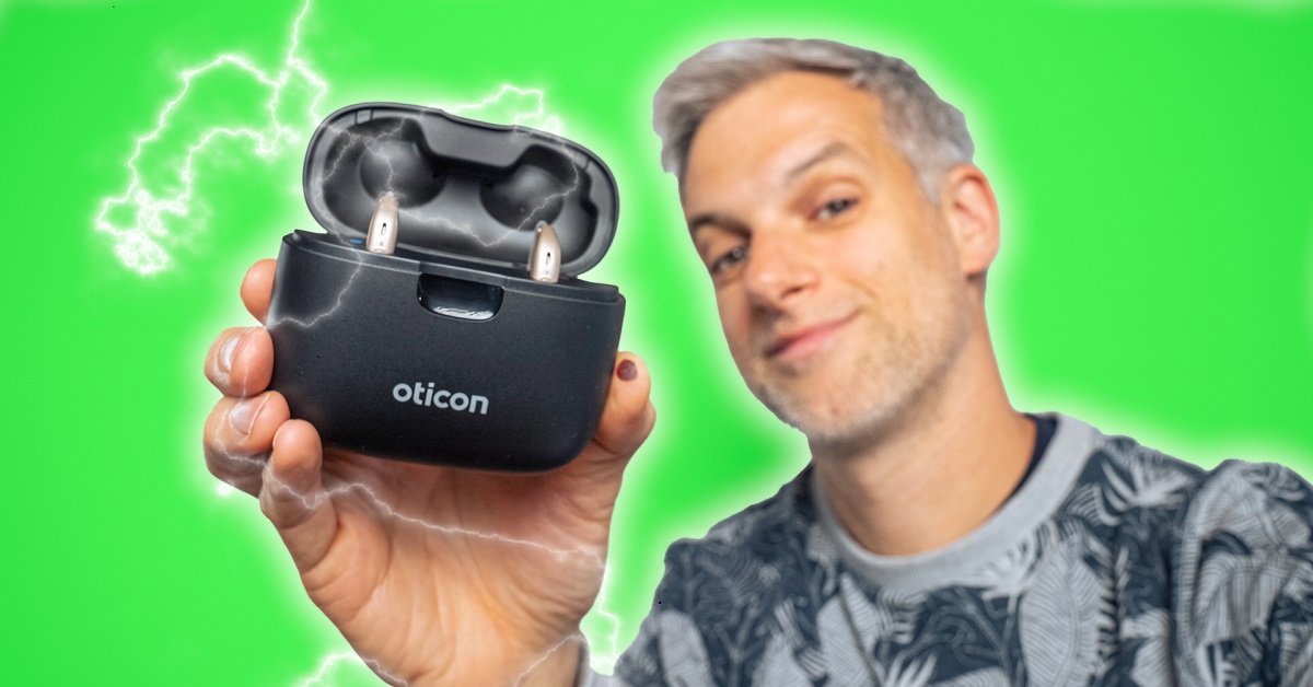 Le youtubeur Monsieur GRrr sur fond vert qui tient à la main des aides auditives Oticon More dans leur smart charger