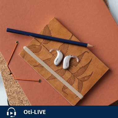 Une paire d'appareils auditifs Oticon  posée sur un carnet