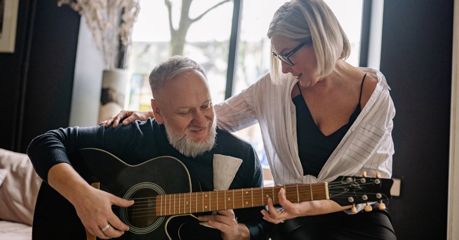 une personne malentendante équipée d'aides auditives fait de la guitare accompagnée de sa compagne
