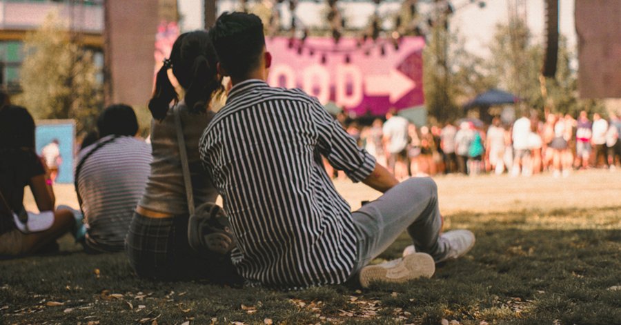 deux personnes assises sur l'herbe à un festival de musique