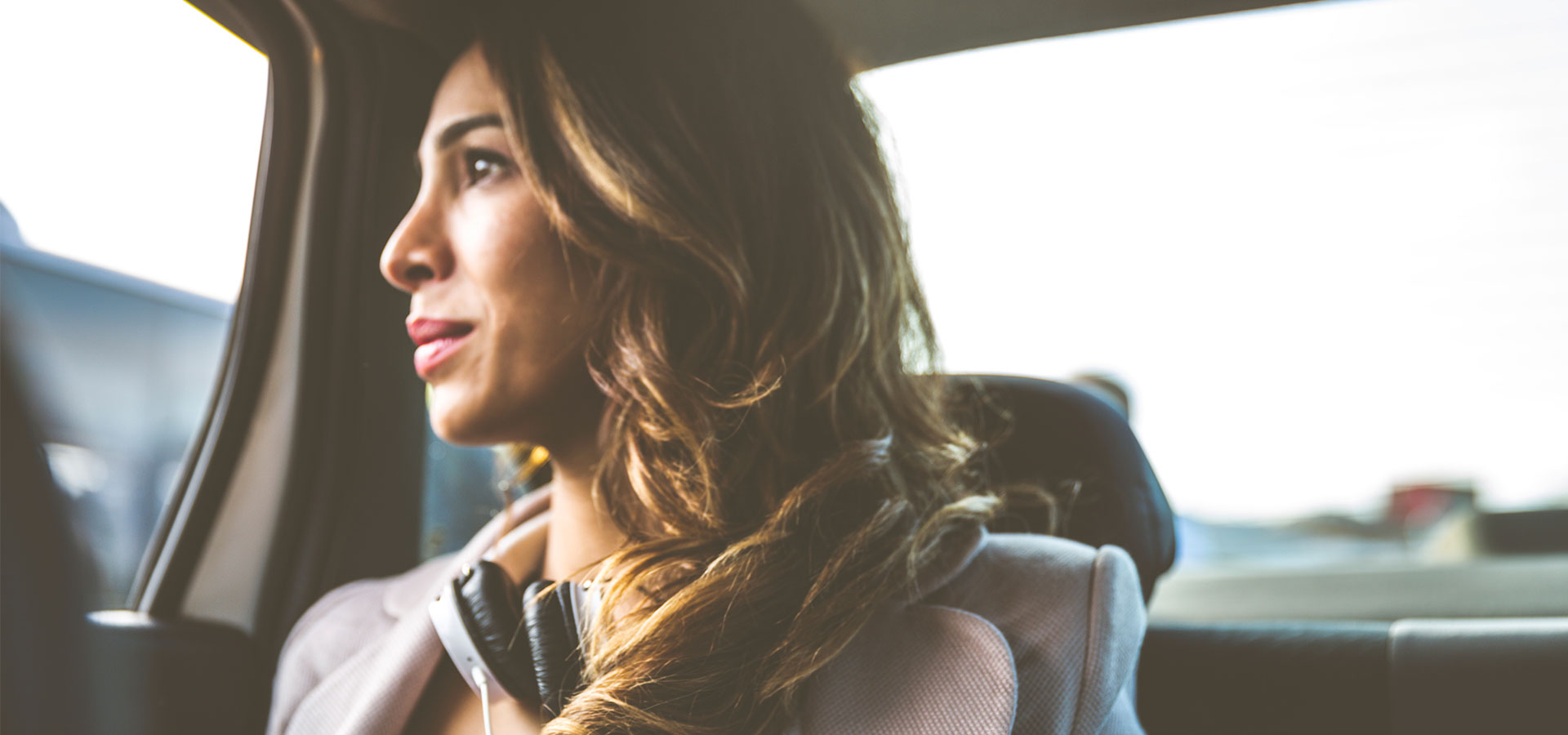 femme aux cheveux ondulés dans une voiture regardant par la fenêtre