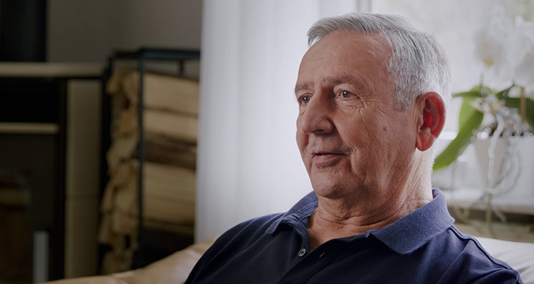 Older man in his living room talking about the benefits of wearing Philips Hearlink hearing aids