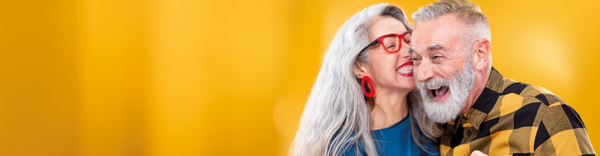 Una mujer de mediana edad abrazada y susurrando un secreto a un amigo. Él lleva aparatos auditivos recargables Philips HearLink.