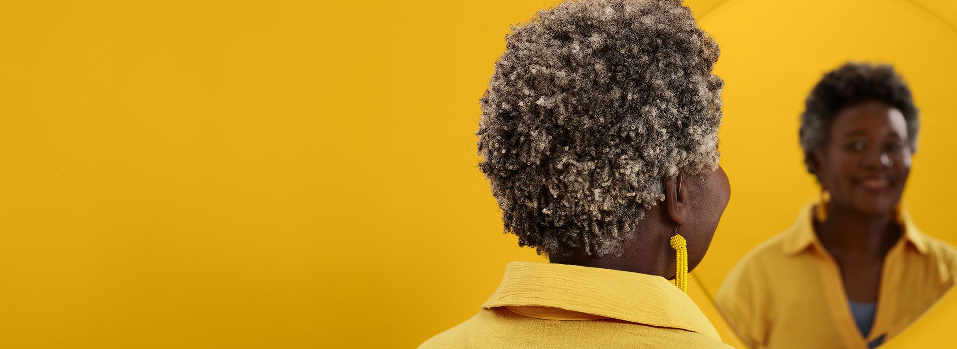 A granddaughter holds a teddy bear while sitting on the back of her grandfather who wears Philips HearLink hearing aids. Her mother also reaches out to hold her daughter.