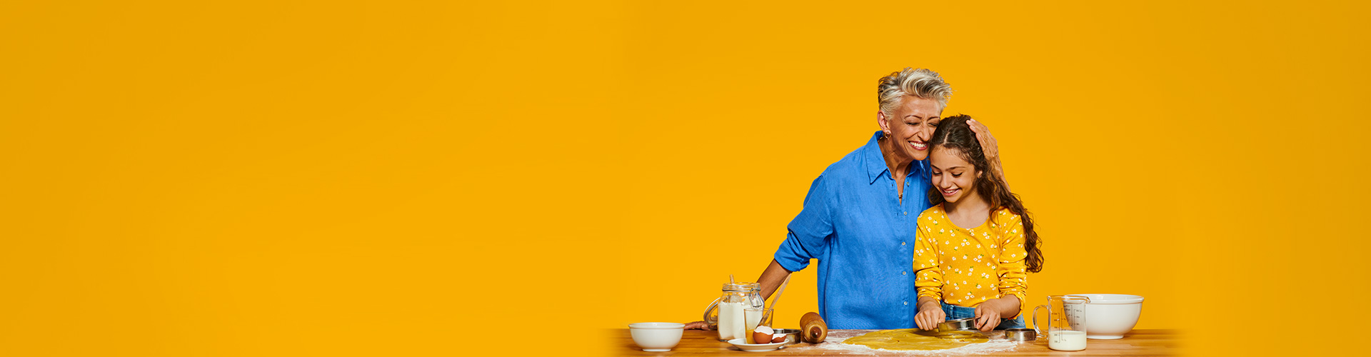 Een oma die Philips HearLink draagt en geniet van een kostbaar moment met haar kleindochter die koekjes bakt.