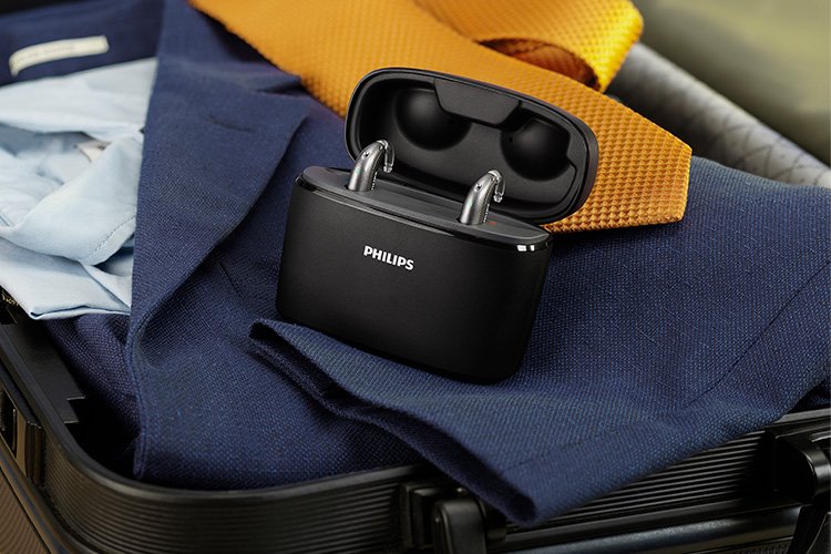 Philips HearLink hoortoestellen in de mini achter-het-oor uitvoering (miniBTE T R) laden op in de draagbare Charger Plus in een ingepakte koffer met kleding