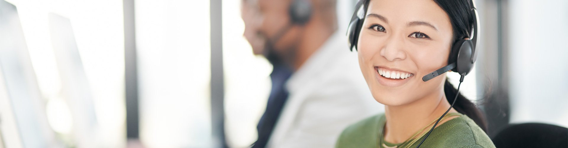 Mulher a falar ao telefone e a ajudar uma cliente com os seus aparelhos auditivos.