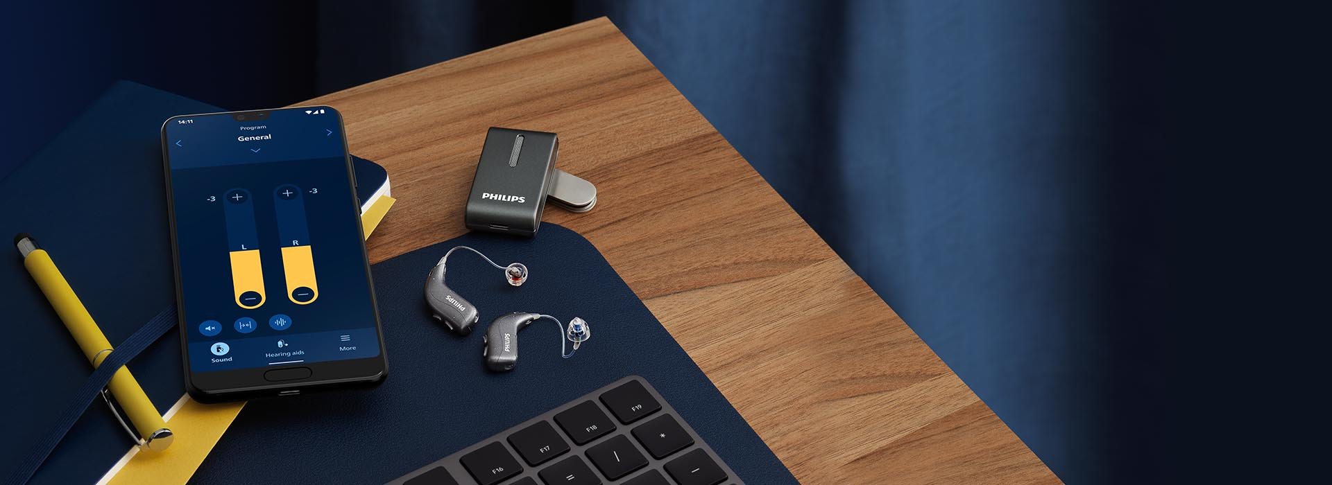 Philips HearLink miniRITE hearing aids next to Philips AudioClip and a smartphone with the Philips HearLink app 2 open.