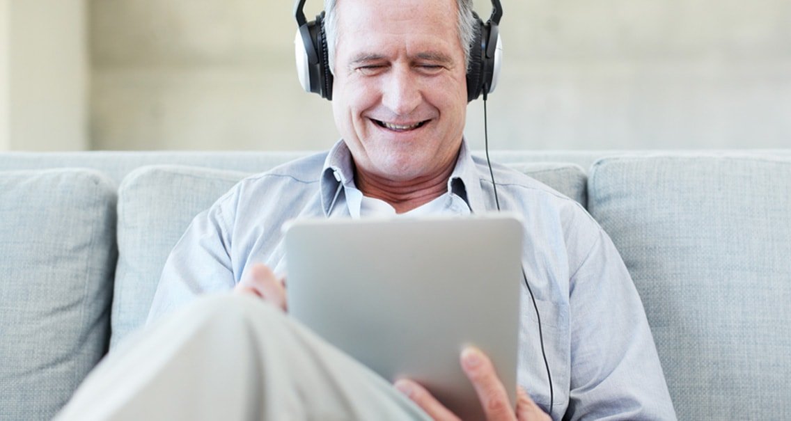 Kanepede otururken çevrimiçi işitme testi ile işitme duyusunu kontrol eden adam 